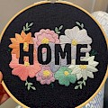 "Home" embroidery hoop utilising a negative space design. Pastel flowers on a dark blue background.