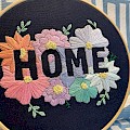 "Home" embroidery hoop utilising a negative space design. Pastel flowers on a dark blue background.