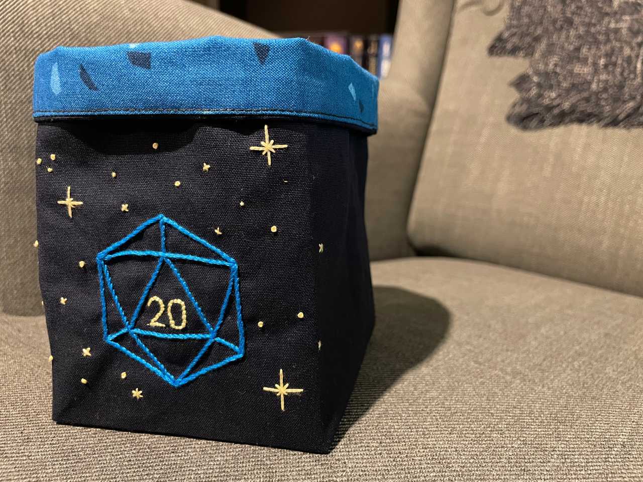 Dice bag embroidered with an outline of a d20 and stars.